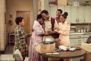 American actors Ralph Carter, Esther Rolle, John Amos, Jimmie Walker, and BernNadette Stanis gather in the kitchen in a scene from the television show 'Good Times,' Los Angeles, California, 1975