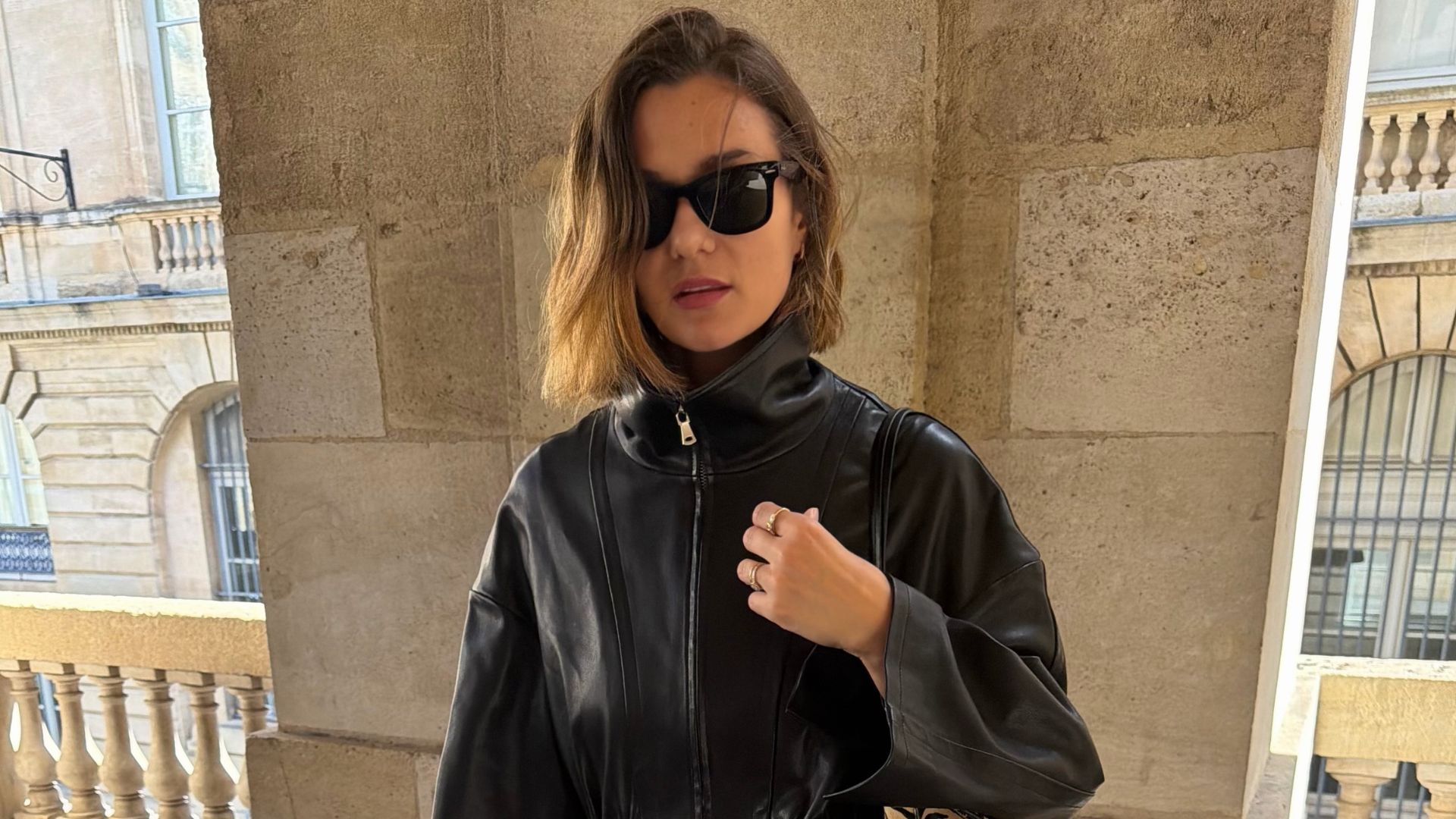 Influencer @annelauremais wears a black leather jacket with blue jeans, white heeled shoes and a tiger print bag.