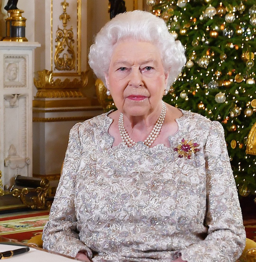 Queen Elizabeth sitting in front of a lit Christmas tree