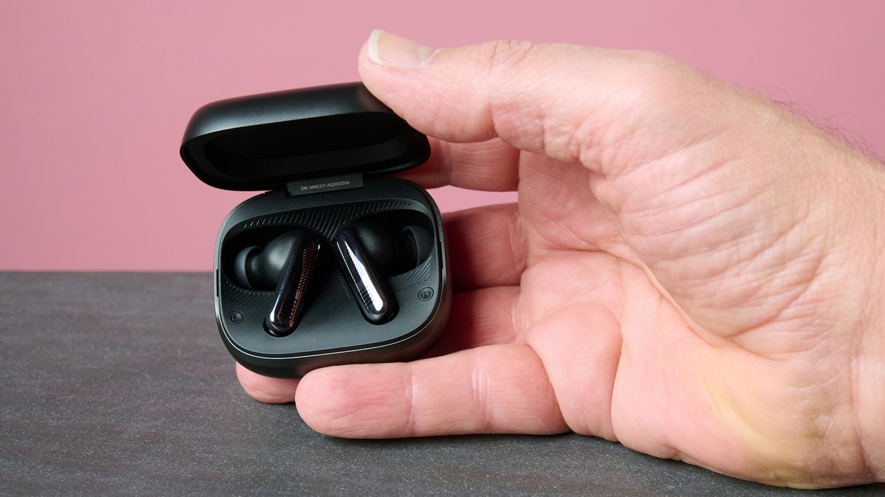 Man holding the JBL Live Beam 4 in their charging case