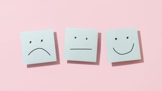 three sticky notes with different faces on pink background