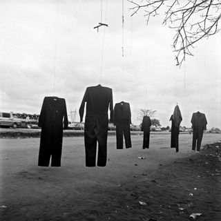 Photography by Jo Ractliffe, Roadside stall on the way to Viana, 2007 of overalls hanging from a tree