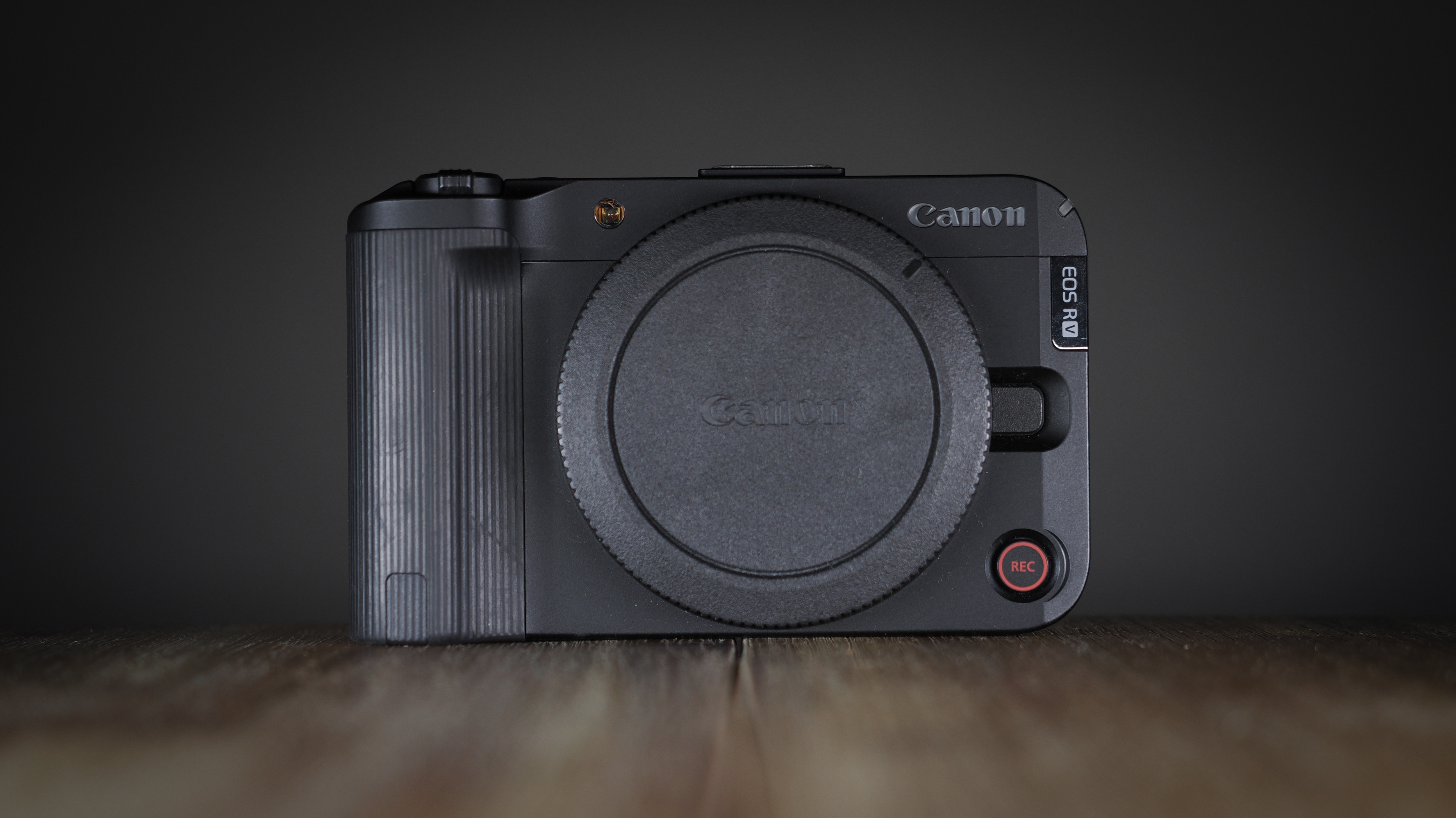 Canon EOS R50 V on a wooden surface, against a dark background