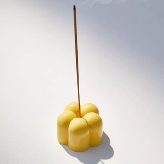 A yellow flower-shaped incense and taper candle holder