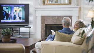 Senior couple sitting on sofa, watching television