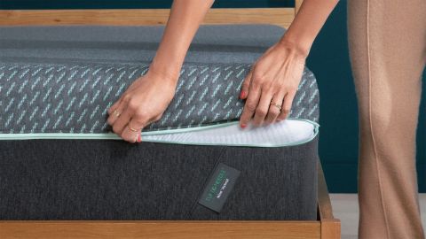 A person zipping up the corner of a Tuft & Needle Mint Hybrid mattress