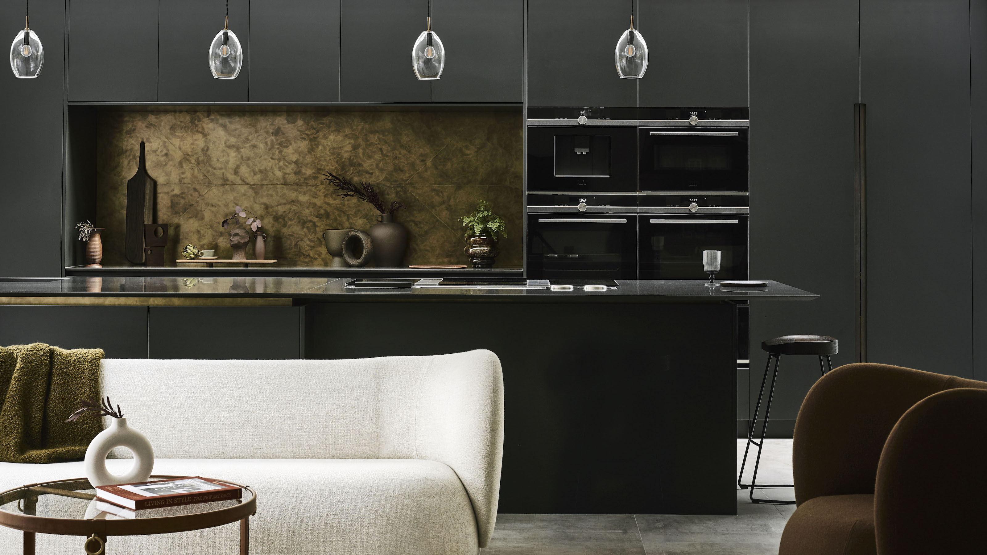 dark kitchen with bronze splash back and white sofa