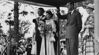 Queen Elizabeth II (centre) and the Duke of Edinburgh (right) waving to the gathered crowd, with the Mayor of Casino, Alderman Manyweathers (left), at Carrington Park, New South Wales, February 15th 1954.