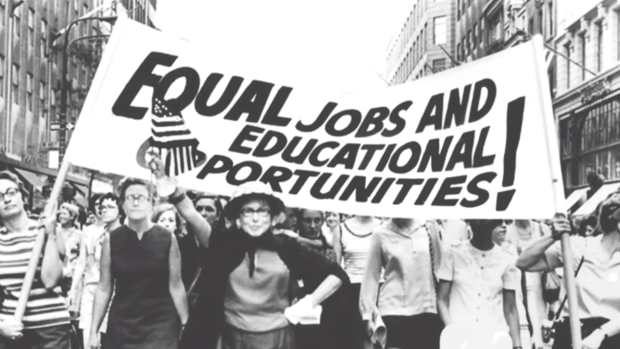 Protesters march with signs in “She is beautiful when she is angry”