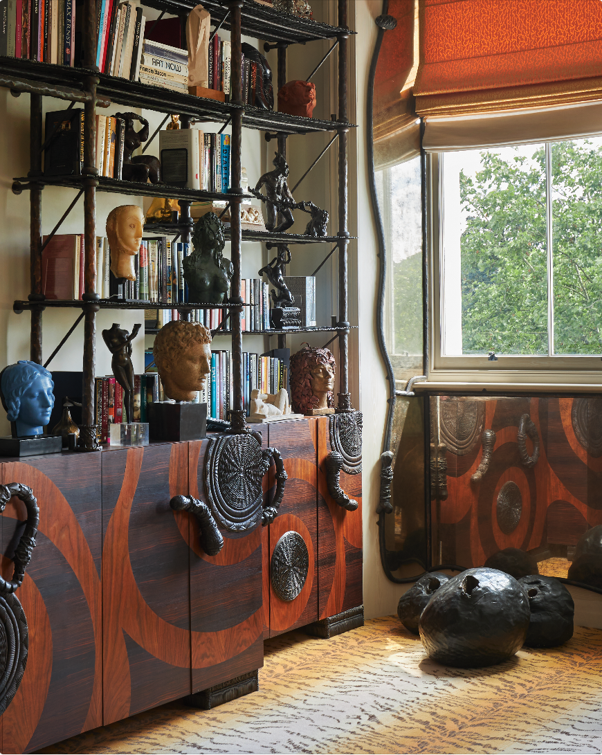 An animal print rug, dark brown bookshelf with swirls on and sculptures and books adoring the bookshelf.