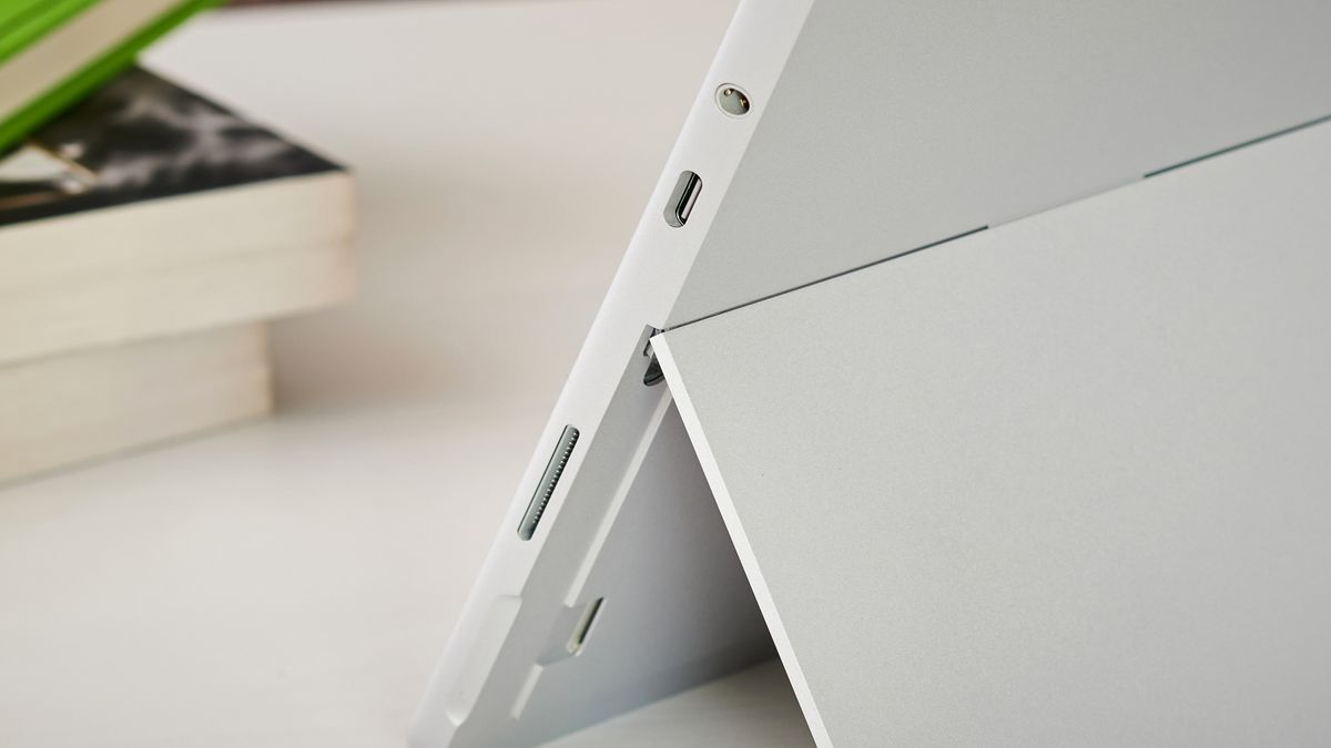 Microsoft Surface Go 2 on a white coffee table next to a stack of books, showcasing its ports