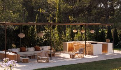 An outdoor kitchen and seating area covered with wooden beams