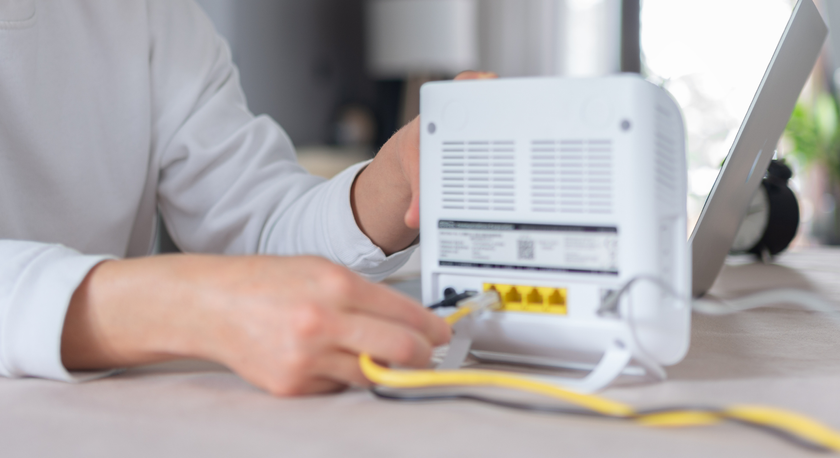 A person plugging an Ethernet cable into a router