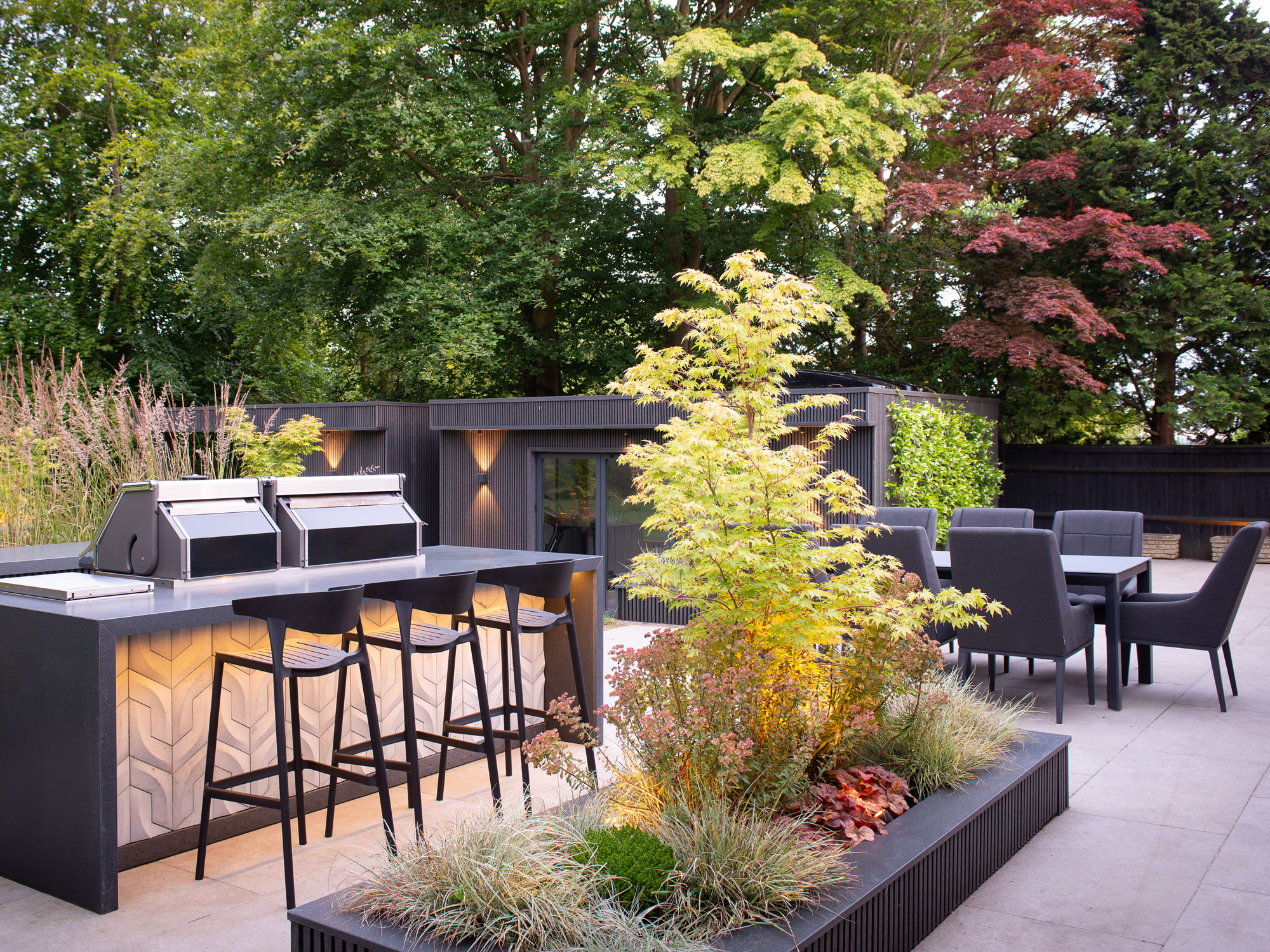 modern patio with island planting bed, outdoor kitchen, and outdoor dining area