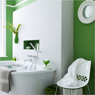 bathroom with white and green wall with bathtub chair and towel