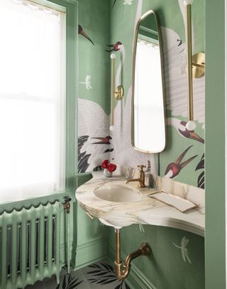 A powder bathroom with a deep green wallpaper