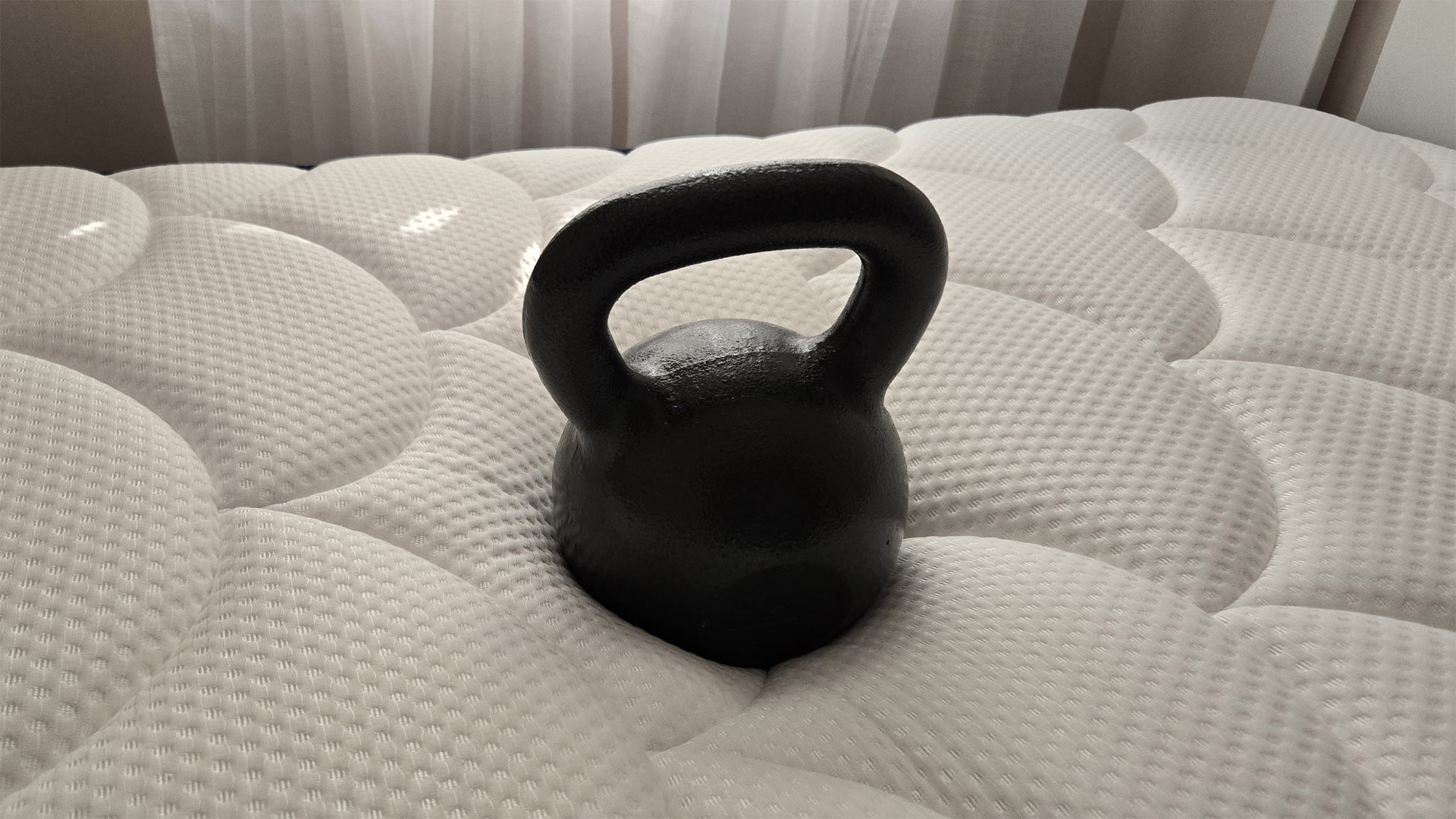 A 50lb kettlebell at the center of the DreamCloud Classic Memory Foam Mattress to gauge pressure relief