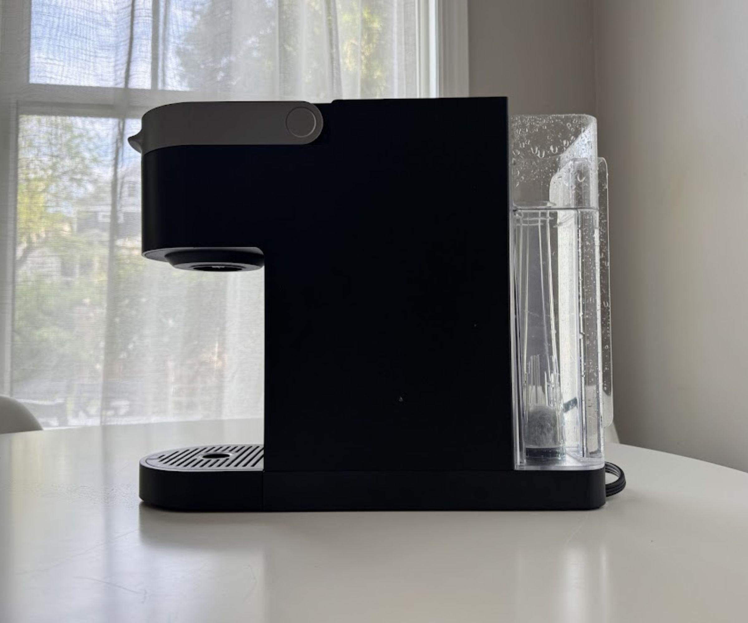 A side view of a black Keurig coffee maker with a clear reservoir at the back.