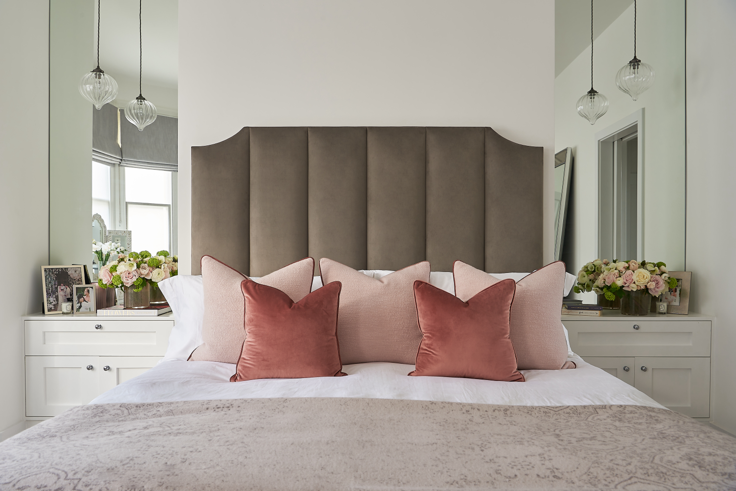 Bedroom with double bed with velour headboard and mirrors in alcoves either side