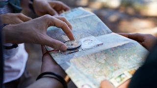 Map spread out across pairs of hands with compass