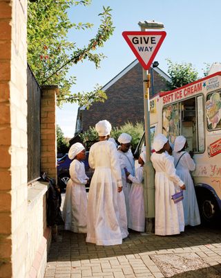 Females wearing white religious clothing outside of an ice cream van