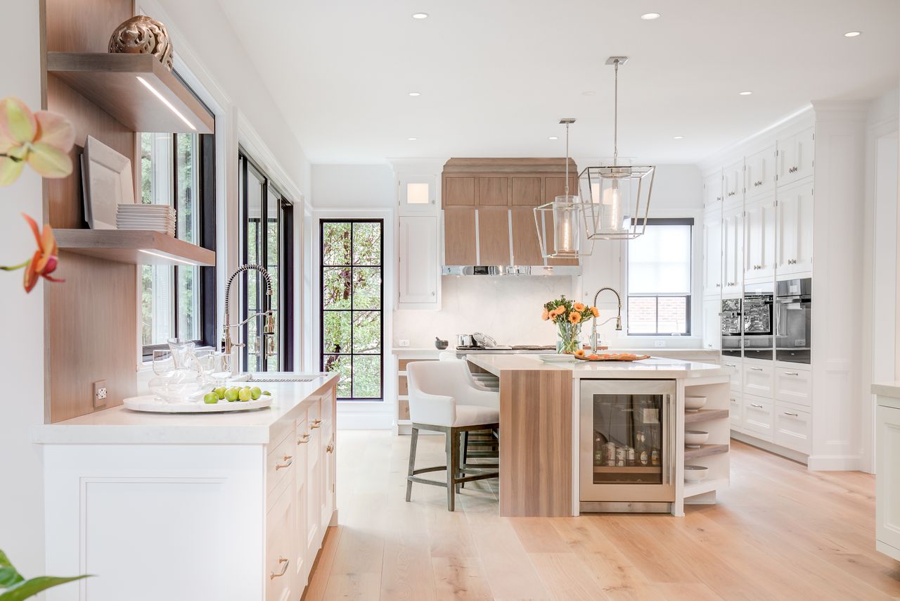 A bright white open plan kitchen with wooden flooring and black framed windows