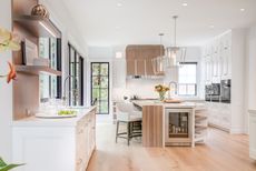 A bright white open plan kitchen with wooden flooring and black framed windows