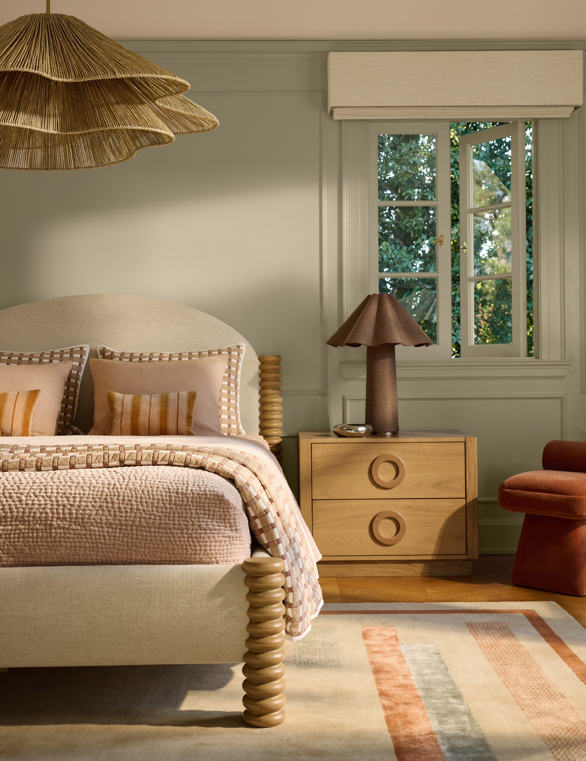 Soothing green bedroom featuring a sculptural bedframe with spiral-wood posts and ruffle-detail lighting