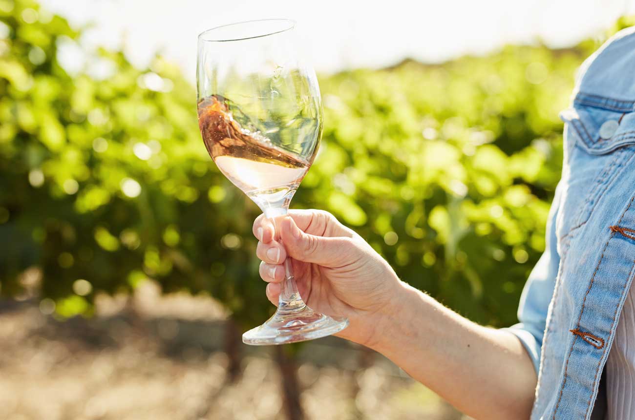 Woman swirling glass of ros&eacute; in vineyard