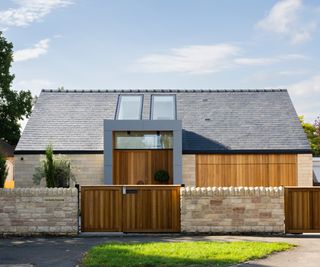 contemporary self build bungalow with black slate roof, light brick and timber clad exterior, with large modern porch and front door