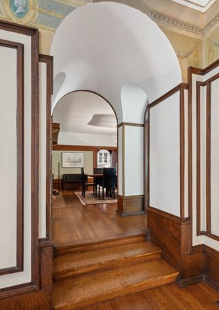 Steps leading up to an arched doorway with wooden floors and trim