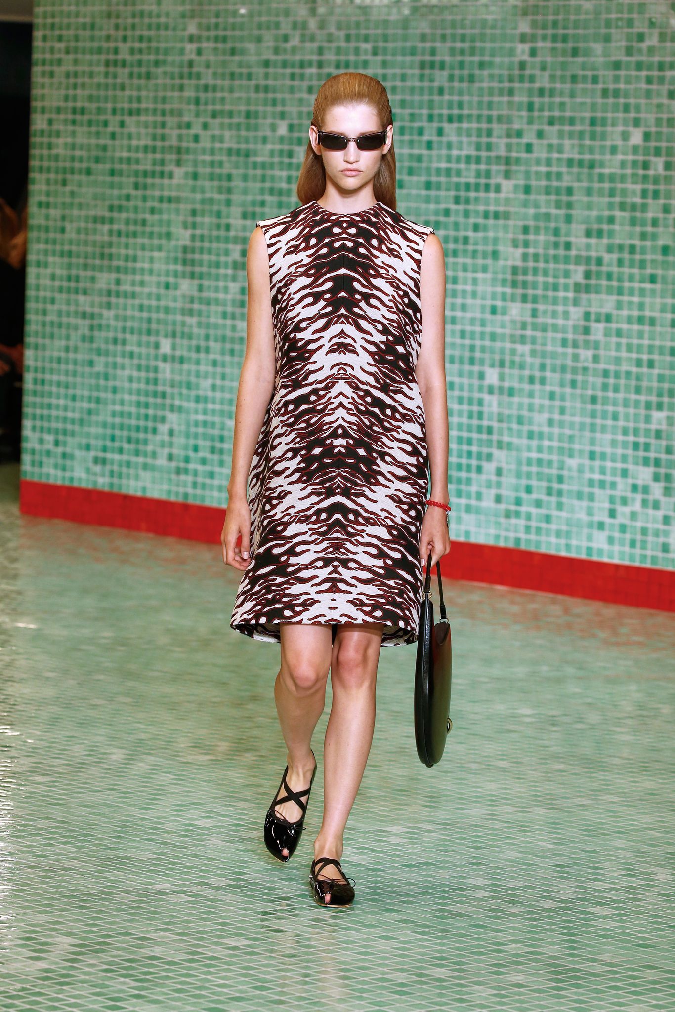 a model wears a printed shift dress on the runway