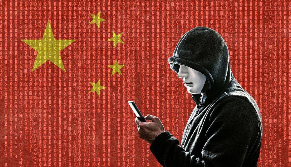 A man wearing a hoodie looks at a smartphone against a backdrop of a Chinese flag overlaid with &#039;Matrix&#039;-like streams of digits.