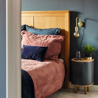 Navy painted bedroom, wooden headboard with pink and blue bedding, bedside table