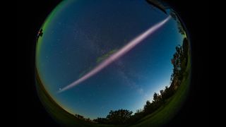 A fish-eye-lens photo of STEVE, the mysterious purple river of light, hanging in the sky over Canada