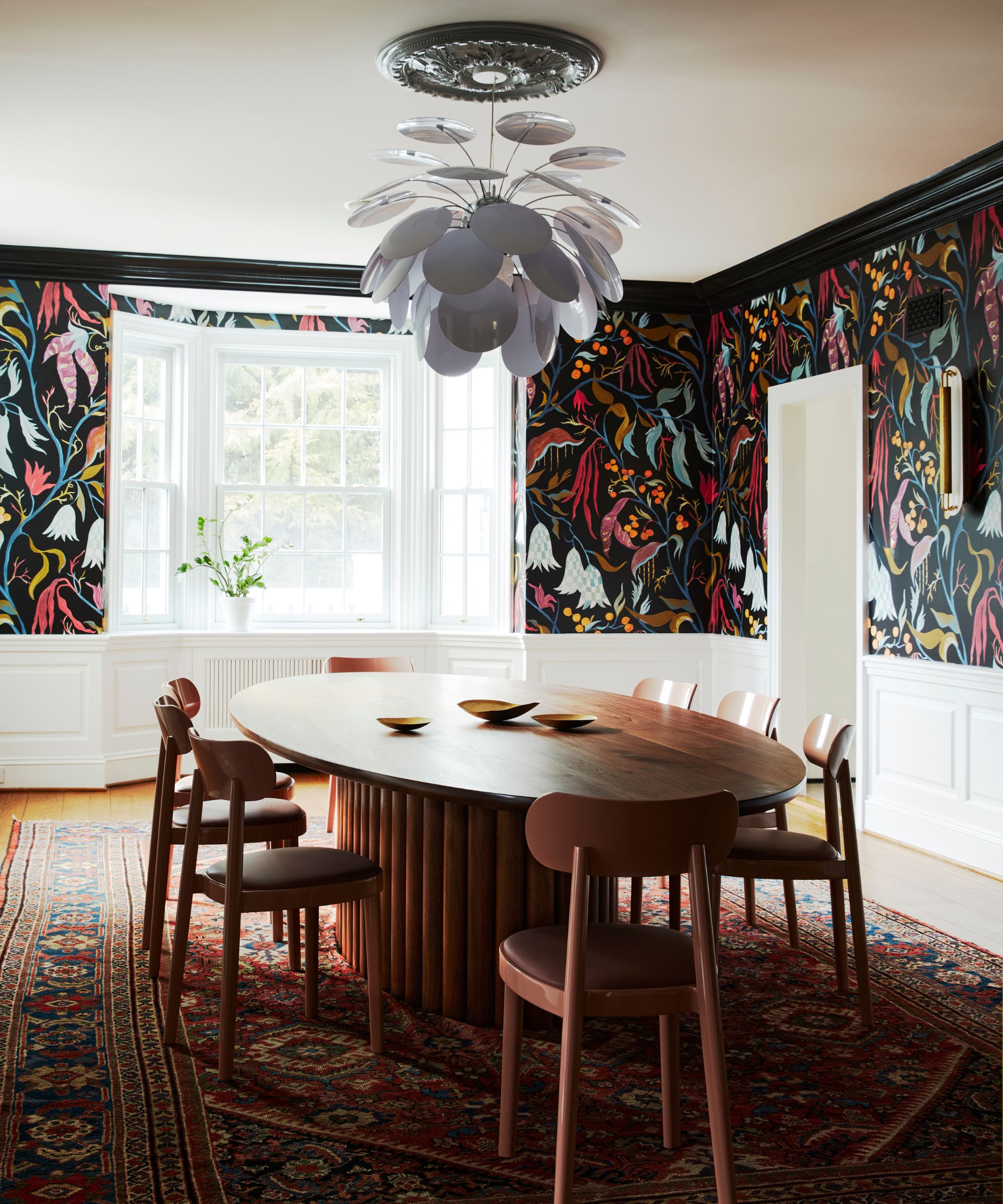 dining room with colorful wallpaper on black background, white ceiling, and large wooden oval dining table and chairs