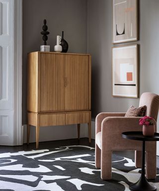 living room with monochrome statement rug, wooden cabinet and pink velvet upholstered chair
