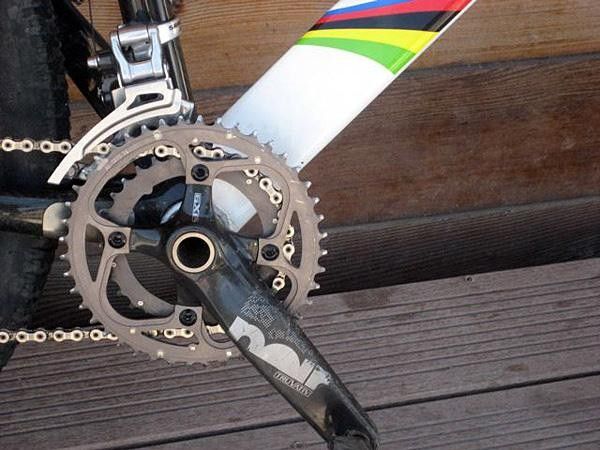 Truvativ's Noir crankset set against a rainbow-striped backdrop.