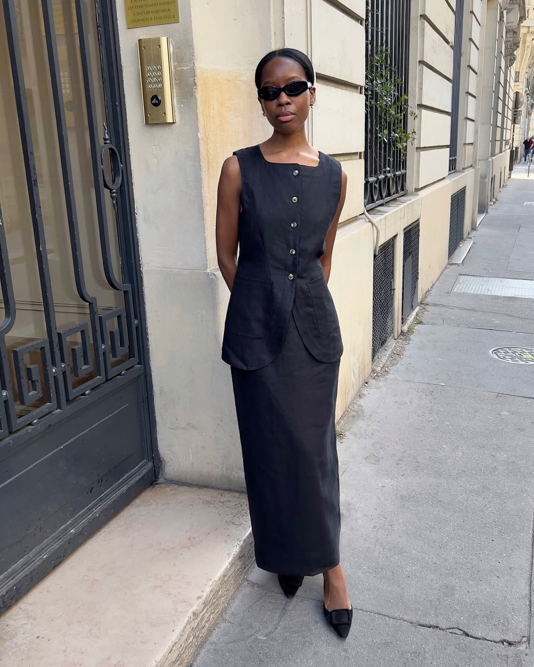 Woman in black linen vest and skirt.