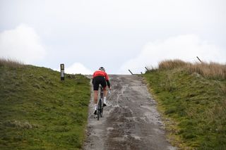 Cyclist Simon Warren climbing on rough tarmac