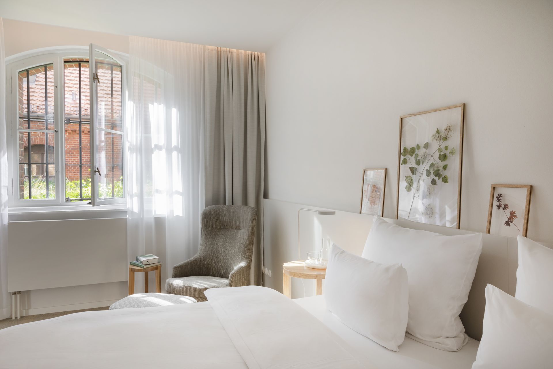 white bedroom with grey chair and framed nature art