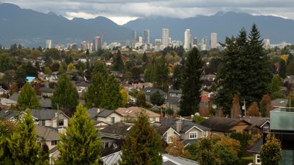 Suburban houses are seen with downtown Vancouver in the distance.
