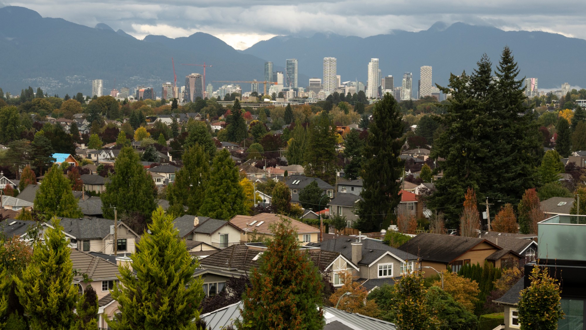 Suburban houses are seen with downtown Vancouver in the distance. 