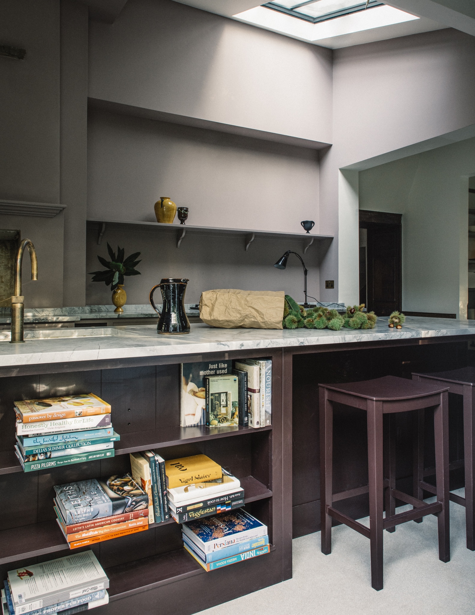A two tone plaum kitchen with open shelving in the island to store books next to the breakfast bar area