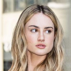 Grace Van Patten wearing a navy collarless blazer, short navy skirt, and pointed-toe heels