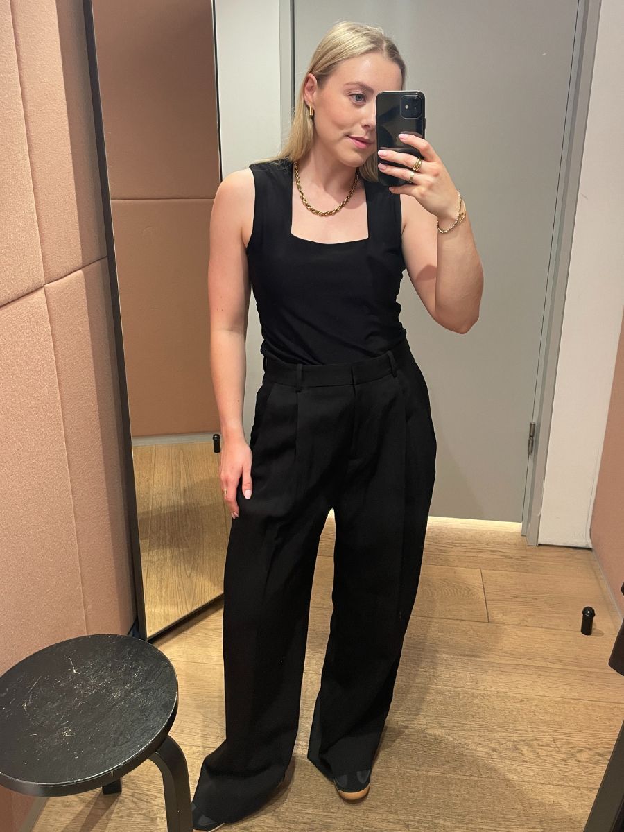 Woman wears black square neck top and black tailored trousers