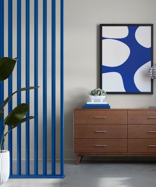 modern entryway with bright blue divider wall, wooden cabinet, bright blue artwork