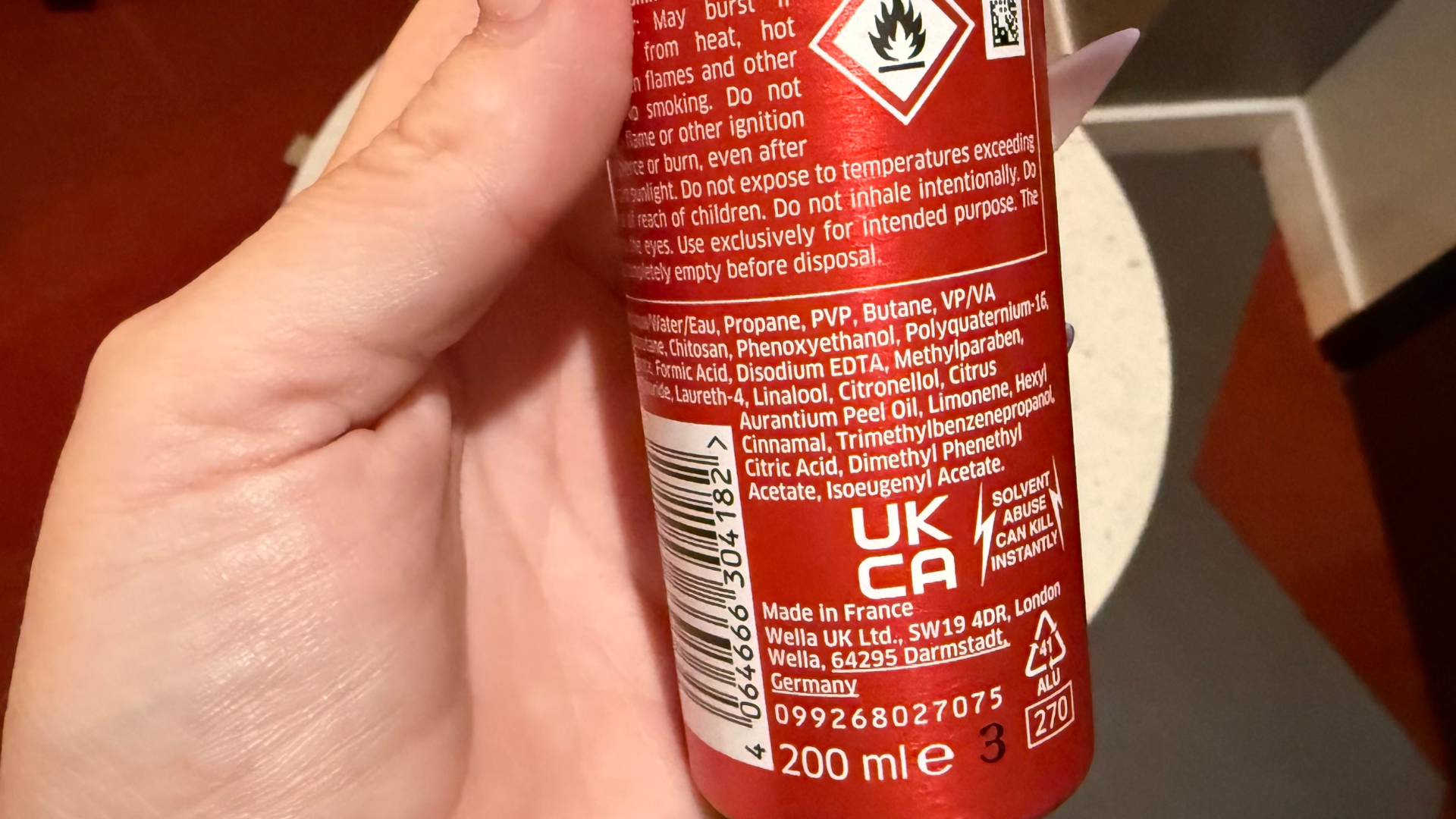 Close-up of the back of a red Wella Shockwaves mousse can showing the ingredients list, hazard warning symbol, and small-print safety information