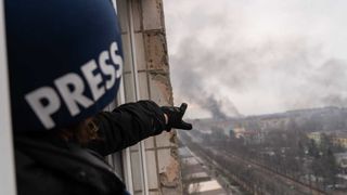 Photographer Evgeniy Maloletka points at the smoke rising after an airstrike on a maternity hospital in Mariupol, Ukraine, March 9, 2022