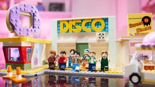 Lego BTS Dynamite sets with the Disco building in the background and Minifigs of the full band